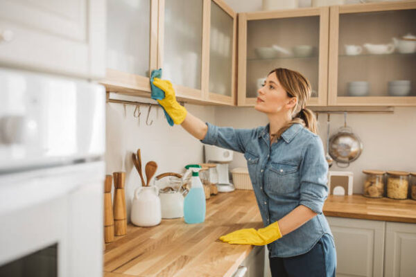 Mulher realizando limpeza profunda em cozinha, com foco na remoção de sujeira e gordura de superfícies e eletrodomésticos.