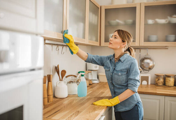 Mulher realizando limpeza profunda em cozinha, com foco na remoção de sujeira e gordura de superfícies e eletrodomésticos.